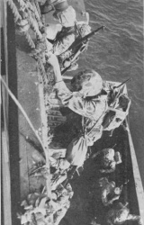 Troops climbing down cargo nets into landing craft